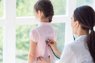 Doktorun muayenehanesinde çocuklu bir çocuk doktoru.