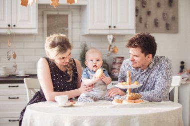 Sevgi dolu bir aile. Bebek çocuk mutfakta tatlı çörek yiyor.