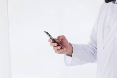 Sağlık hizmetleri, tıp konsepti: Beyaz önlüklü erkek doktor dokunmatik ekranlı akıllı telefon cihazı kullanıyor