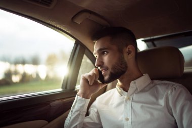 Akıllı telefondan konuşan adam arabanın arka koltuğunda oturuyor, iş adamı takside.