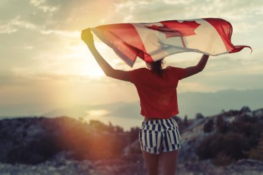 Mutlu çocuk genç kız gün batımında koşarken Kanada bayrağını sallıyor