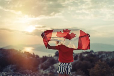 Mutlu çocuk genç kız gün batımında koşarken Kanada bayrağını sallıyor