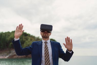 İş adamı, deniz arka planında sanal gerçekliği görüntülemek için VR-kulaklık kullanır
