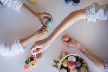                                Mutlu ergenler kız arkadaşları evde renklilerle ve fırçayla yumurta boyuyor. Paskalya, tatiller ve insanlar konsepti       