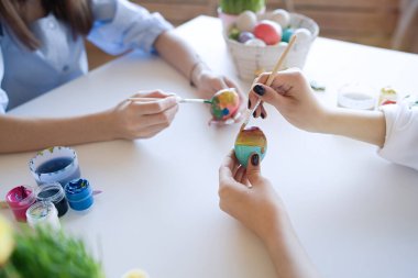                                Mutlu ergenler kız arkadaşları evde renklilerle ve fırçayla yumurta boyuyor. Paskalya, tatiller ve insanlar konsepti       