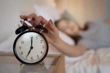                           Uykulu genç kız, sabahları yatakta yatarken alarmı kapatıyor. Erken kalkmak, uykusuzluk, iş kavramı.      
