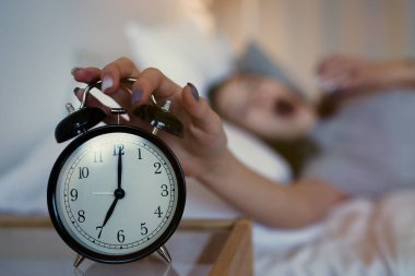                           Uykulu genç kız, sabahları yatakta yatarken alarmı kapatıyor. Erken kalkmak, uykusuzluk, iş kavramı.      