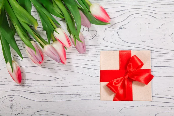 木桌背景上的郁金香花束和礼品盒 — 图库照片