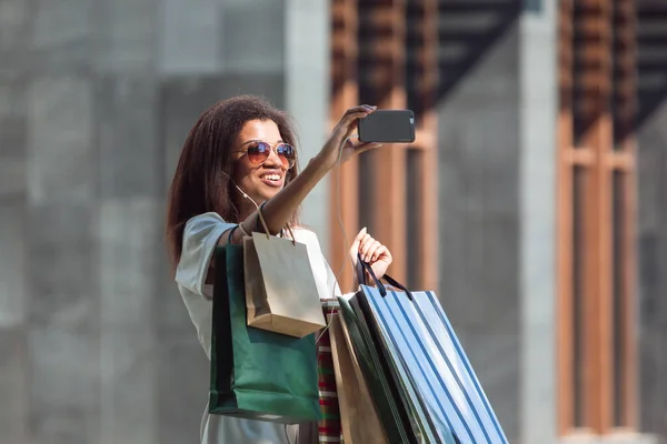 Woman with a shopping bags making a video call via smartphone
