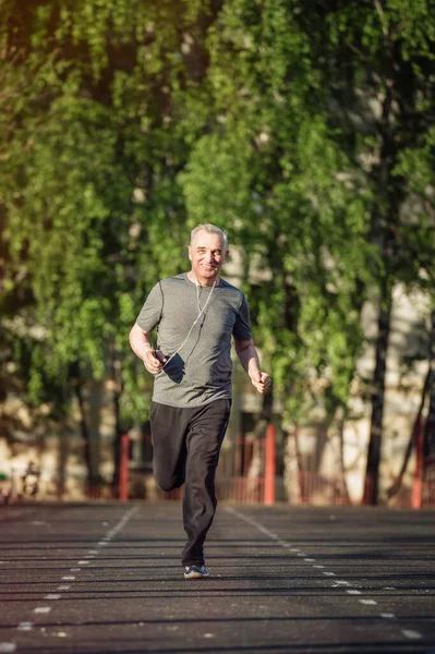 Senior seventy years old man jogging at sunrise. Morning running