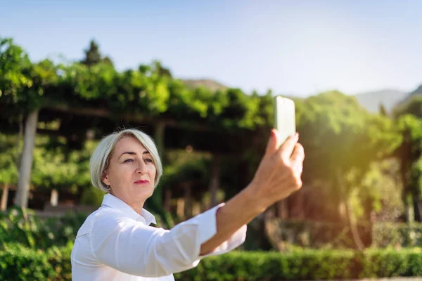 Starsza Kobieta Robi Sobie Selfie Telefonem Komórkowym Podczas Odpoczynku Parku — Zdjęcie stockowe