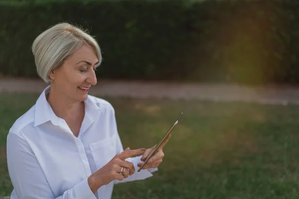 Dojrzała Kobieta Stosująca Tabletki Podczas Odpoczynku Parku Picia Kawy — Zdjęcie stockowe