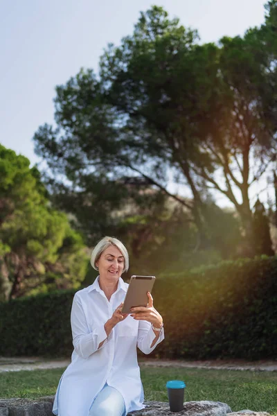 Mulher Madura Usando Tablet Enquanto Descansa Parque Bebe Café — Fotografia de Stock