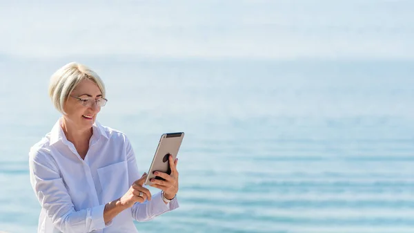 Dojrzała Kobieta Okularach Pomocą Tabletu Tle Morza Błękitnego Nieba — Zdjęcie stockowe