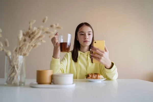 Roztomilé Teen Dívka Jíst Snídani Kuchyni Při Použití Její Chytrý — Stock fotografie