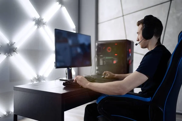 Professional gamer in his expensive studio young man having live stream playing online video game. Cyber sportsman is streaming popular pc computer game for his followers