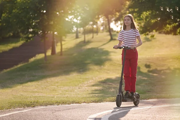 Gün Batımında Parkta Elektrikli Scooter Kullanan Tatlı Bir Genç Kız — Stok fotoğraf