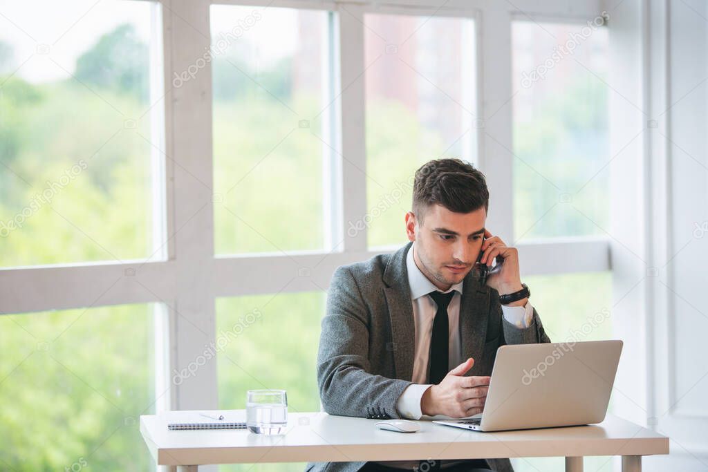 Handsome businessman is talking by phone in a office