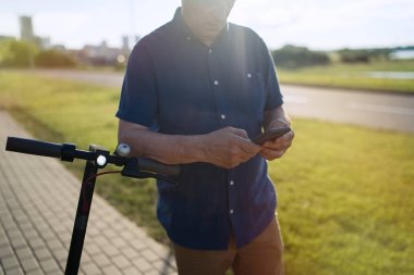                               Son sınıf öğrencisi elektrikli scooterla gezdikten sonra akıllı telefon kullanıyor. 