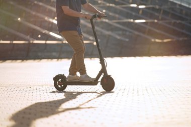                                Son sınıf öğrencisi gün batımında şehirde elektrikli scooter kullanıyor.  