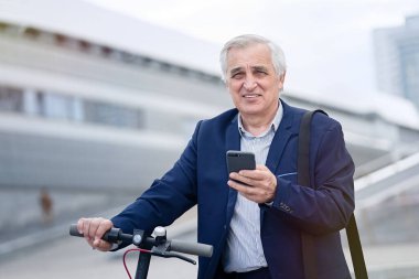                          Kıdemli işadamı elektrikli scooterında telefon kullanıyor.      