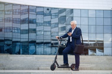                          Kıdemli işadamı elektrikli scooterında telefon kullanıyor.      