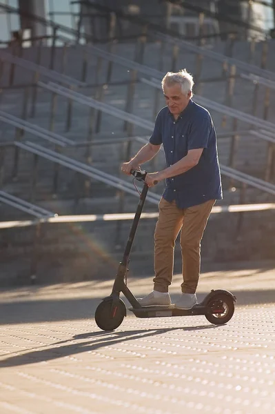 Pria Senior Mengendarai Skuter Listrik Kota Saat Matahari Terbenam — Stok Foto