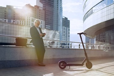                                Kıdemli işadamı elektrikli scooterında telefon kullanıyor.      