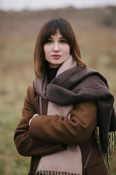 Woman in brown stylish cashmere posing on autumn background.