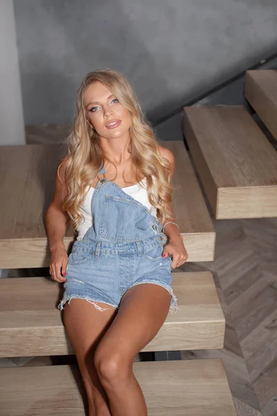 Young sexy blonde in jeans clothes posing on the steps