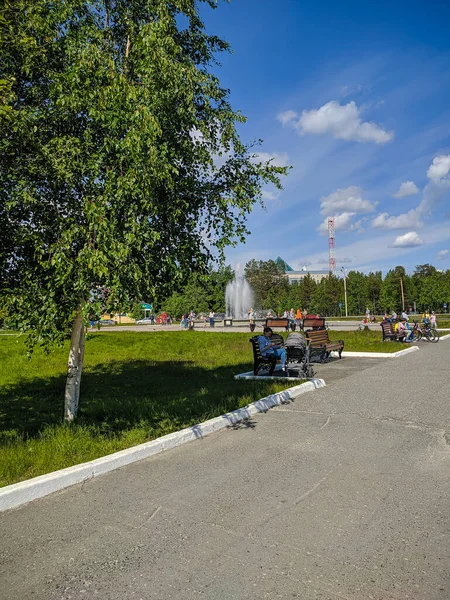 Noyabrsk, Rusya - 30 Mayıs 2020: dinlenmek için şehir meydanı. İnsanlar bankta oturur, fıskiye arka planda çalışır..