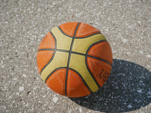 Noyabrsk, Rusya - 9 Ağustos 2020: Beton zeminde gölgesi olan turuncu ve sarı bir basketbol topu. Yakın plan.