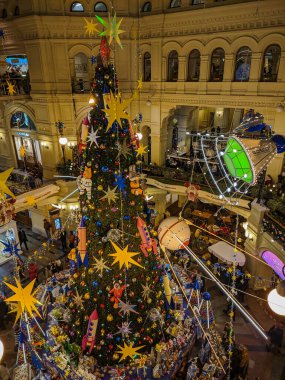 Moskova, Rusya - 1 Aralık 2019 GUM mağazasının içinde. Parlak, renkli Noel süslemeleri ve oyuncaklar binanın ortasında ana ağacın üzerinde asılı. Dikey.