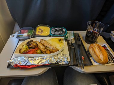 Moskova, Rusya - 1 Aralık 2019: yemek tepsisi. Katlama masasında farklı yemek setleri var. Yemekler uçakta. Yolcu uçağın arka planında yemek yiyor. Dikey.