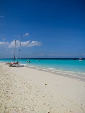 Zanzibar, Tanzanya - 3 Aralık 2019: Zanzibar 'daki Nungwi plajı, parlak mavi deniz ve güzel beyaz bir plajda mavi gökyüzü. Denizcilerin tekneleri balık tutmak ve dinlenmek için kıyıda. Harika bir cennet. Dikey.