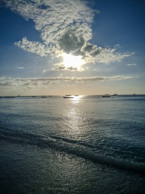 Zanzibar, Tanzanya - 3 Aralık 2019: Zanzibar 'daki Nungwi plajı, batan güneş bulutların arasından gözetliyor. Güzel tropikal beyaz kumsal. Dikey.
