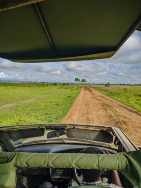 Mikumi, Tanzanya - 6 Aralık 2019: Safari cipinde oturan yolcu koltuğundan görüntü. Sürücü, Mikumi Milli Parkı 'ndaki güzel bir Afrika bölgesinde mola veriyor. Dikey.
