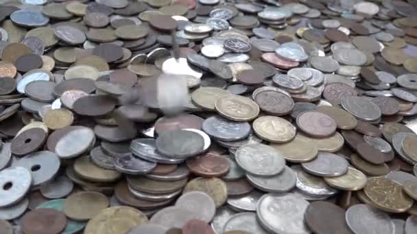 In Zeitlupe fallen viele verschiedene Münzen aus verschiedenen Ländern auf einen Haufen — Stockvideo