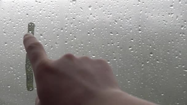 Homme écriture à la main sur la fenêtre brumeuse verre mot inscription "pluie". — Video