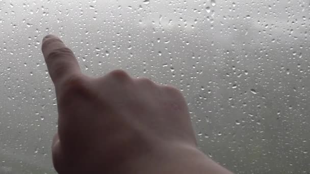 Hombre mano escribir en la ventana nebulosa palabra de cristal inscripción "la lluvia ". — Vídeo de stock