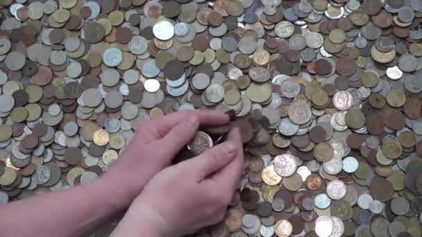 A mão do homem mexe um monte de muitas moedas diferentes de países diferentes em heap — Vídeo de Stock