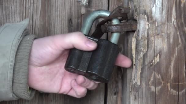 Man hand open and close metal the padlock by key. Ответ: Деревянная дверь — стоковое видео