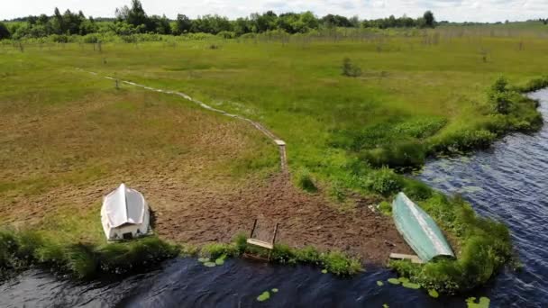 Antennenrote kupferfarbene Sumpfruderboote liegen am Ufer eines Sumpfsees — Stockvideo