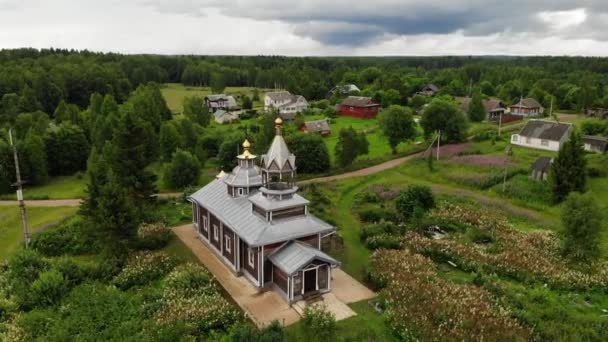 Vista aérea aldeia de madeira com igreja no lago de costa. campo flores lilás. — Vídeo de Stock