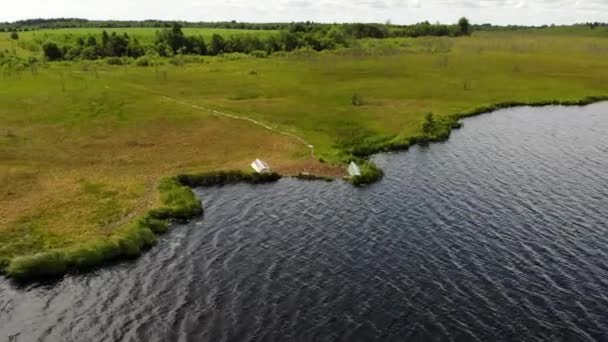 Antennenrote kupferfarbene Sumpfruderboote liegen am Ufer eines Sumpfsees — Stockvideo