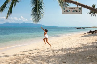 Beyaz elbiseli kız palmiye ağaçları Samui beach adada atlar.