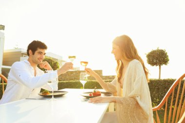 Genç çift deniz kenarındaki otel restoranında yemek yiyor.