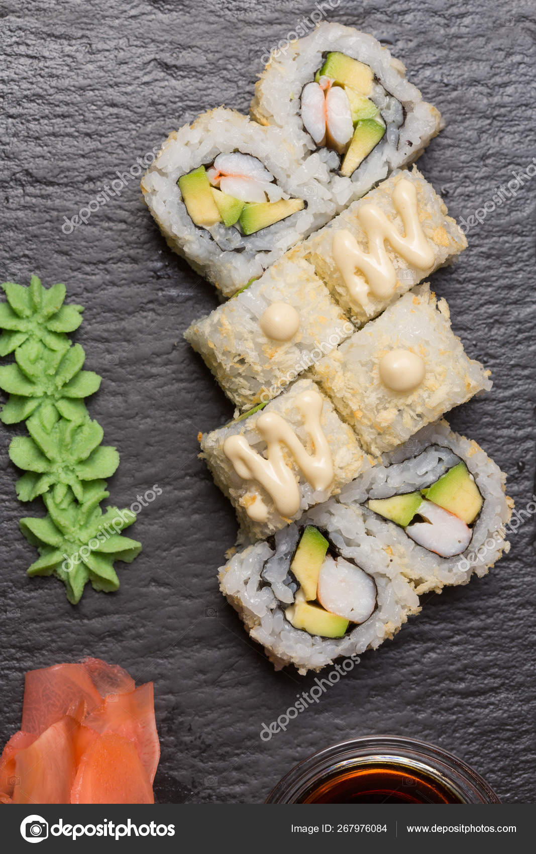 Uramaki sushi with surimi crab, avocado served on black stone ⬇ Stock