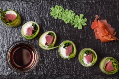 Somon ile salatalık rulo, krem peynir siyah taş üzerinde servis