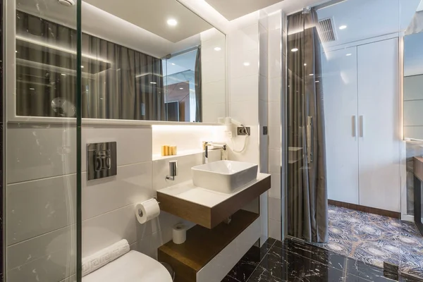 Интерьер роскошной ванной комнаты отеля со стеклянной душевой кабиной — стоковое фото